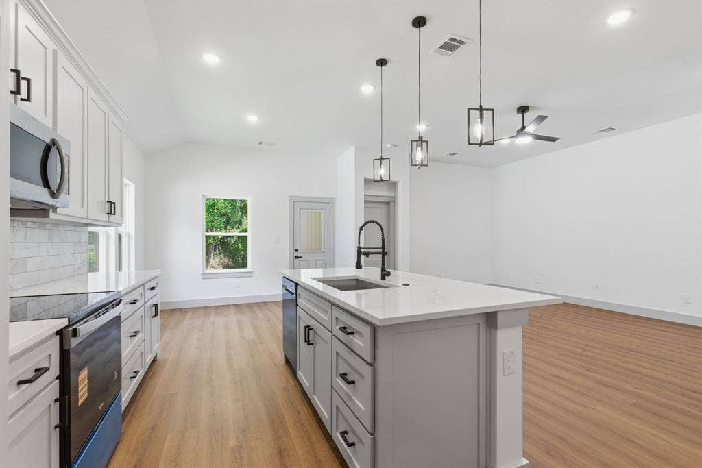 14583 Cherokee Lane, Log Cabin, TX 75148 Modern kitchen featuring light cabinetry, stainless steel appliances, a center island with sink, and wood-finish flooring