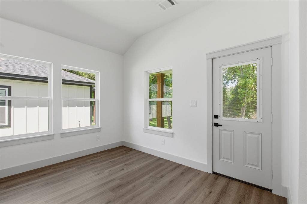 14583 Cherokee Lane, Log Cabin, TX 75148 Vaulted ceiling, wood-finish flooring, multiple windows, white paneled door with glass insert, and white trim throughout