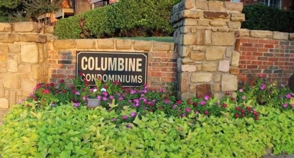 Stone and brick entrance wall with vibrant landscaping