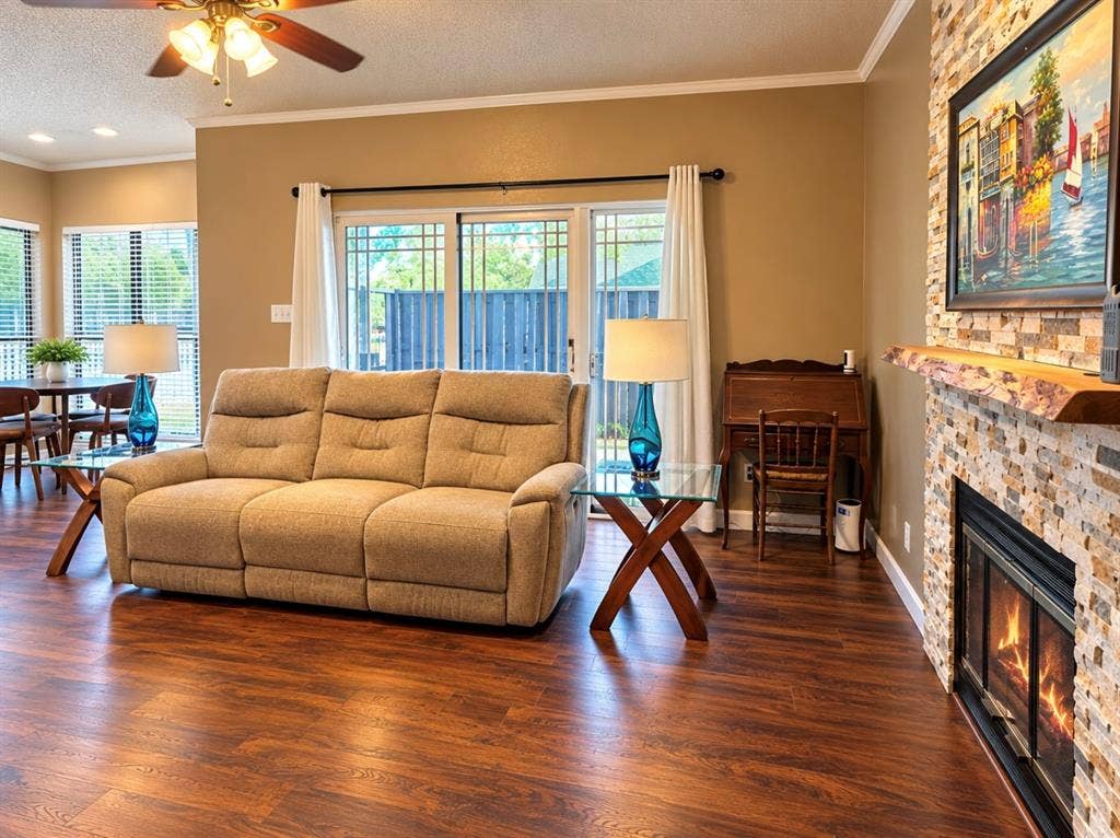 Wood-finish flooring throughout, a stone-clad fireplace with a wood mantel, and sliding glass doors with privacy blinds