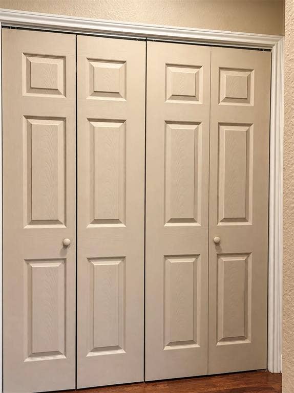 Bi-fold doors with panel detailing, white trim, and wood-finish flooring