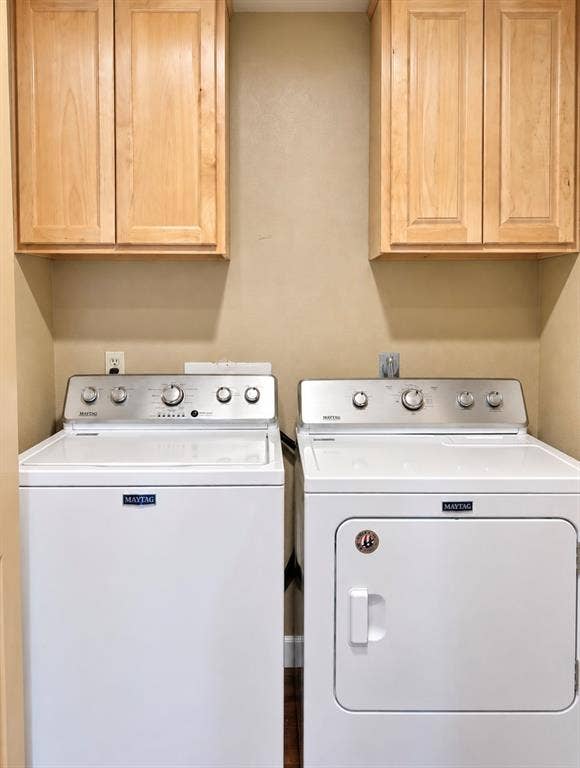 Laundry area with light wood-finish cabinetry and a neutral wall color