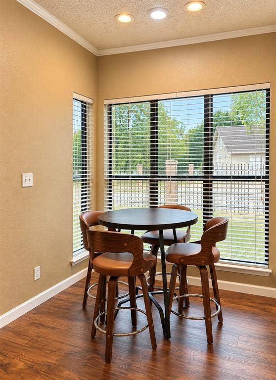 Wood-finish flooring, recessed lighting, crown molding, and multiple windows with blinds