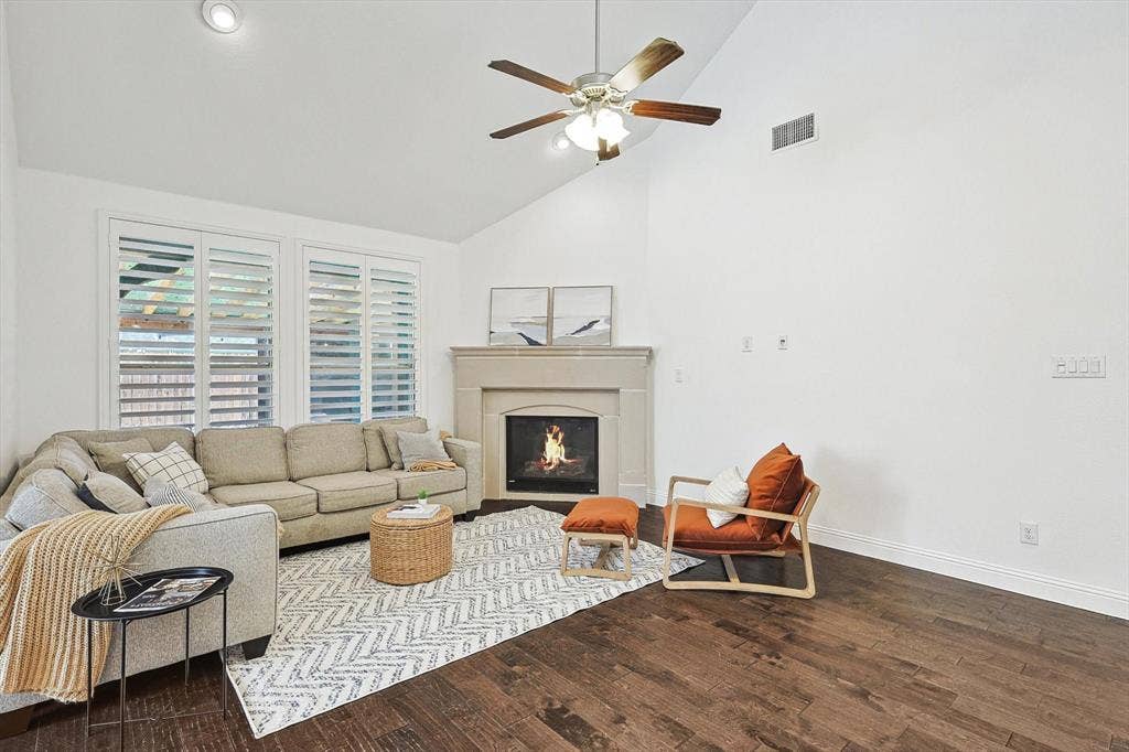 Vaulted ceiling with recessed lighting, stone-finish fireplace, wood-finish flooring, and white plantation shutters