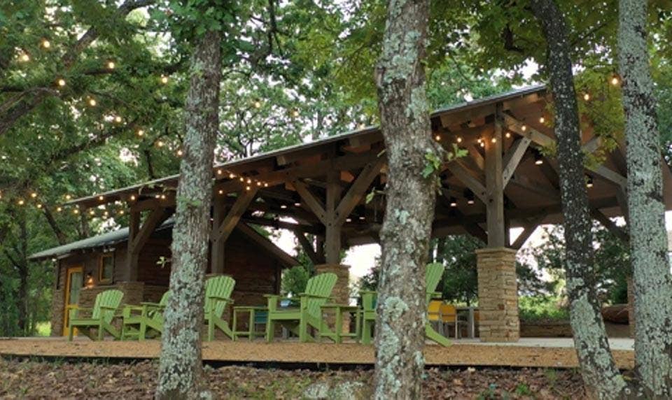 Wood-paneled exterior with a covered porch featuring exposed timber beams and stone pillars