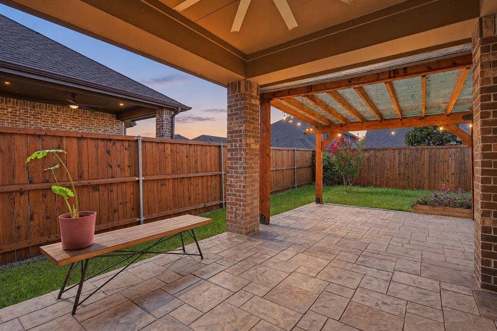 Covered patio with stamped concrete flooring, brick columns, and a wood pergola *virtual twilight added