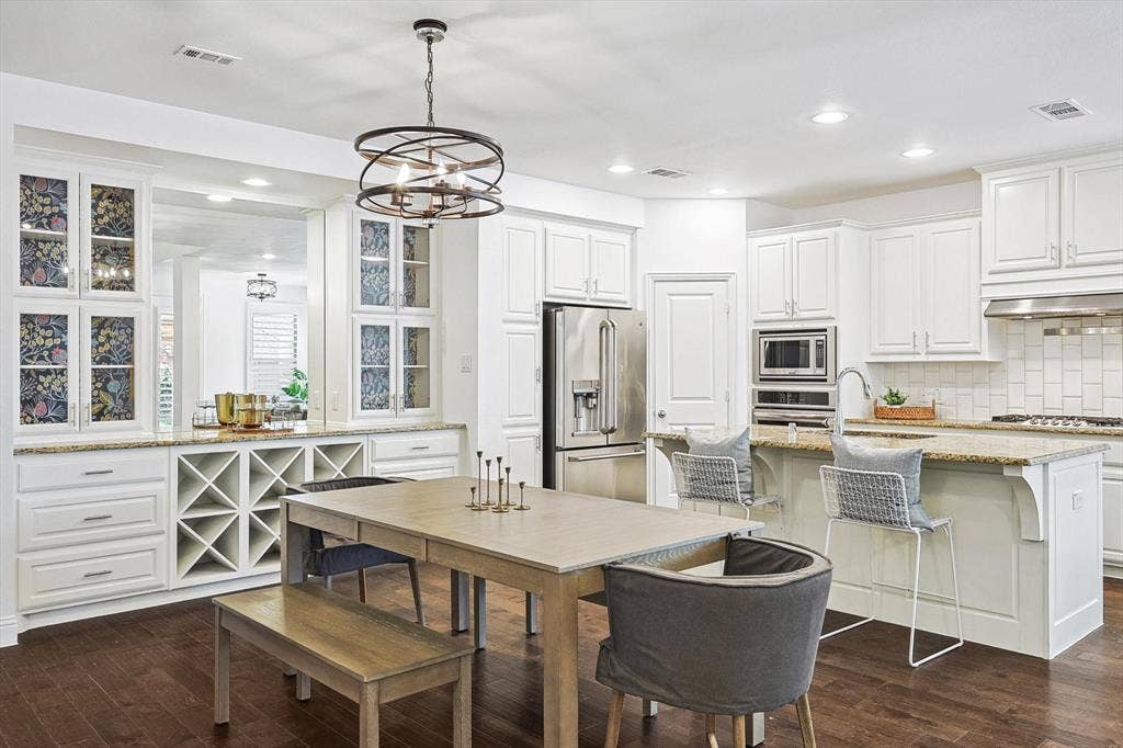 Kitchen featuring wood-finish flooring, white cabinetry, granite countertops, stainless steel appliances, and a built-in wine rack