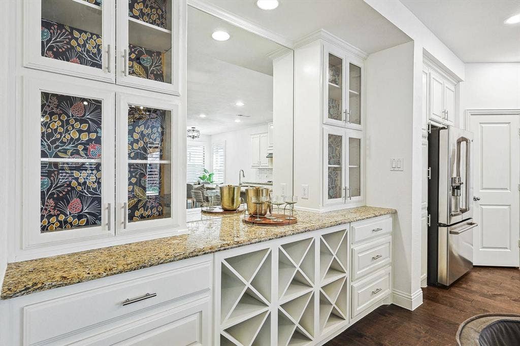 Built-in cabinetry with glass-front uppers, an integrated wine rack, and a natural stone countertop