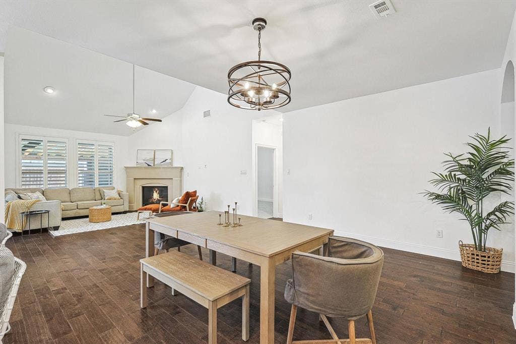 Vaulted ceiling with a ceiling fan, recessed lighting, wood-finish flooring, a stone fireplace, and plantation shutters