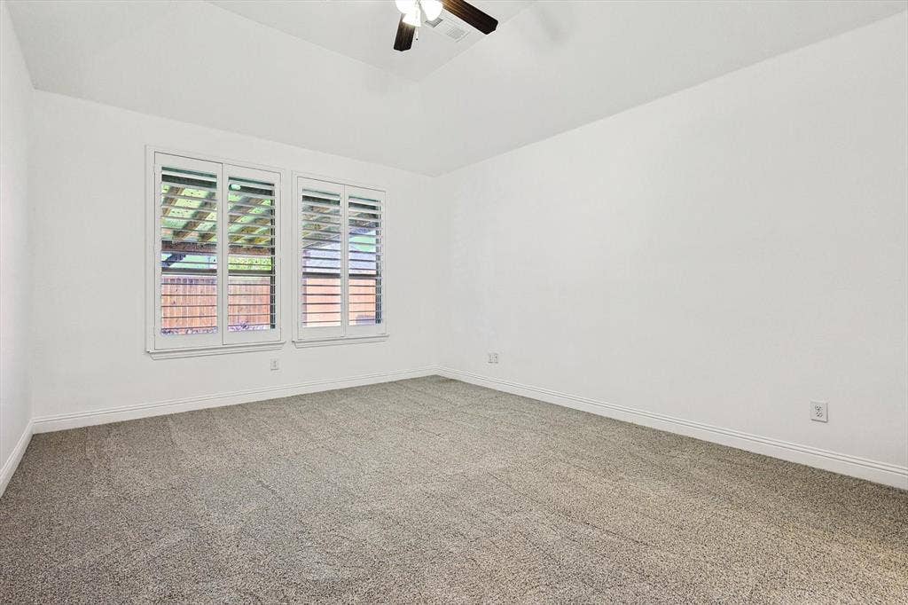 White walls, textured gray carpet, and a ceiling fan with light fixture