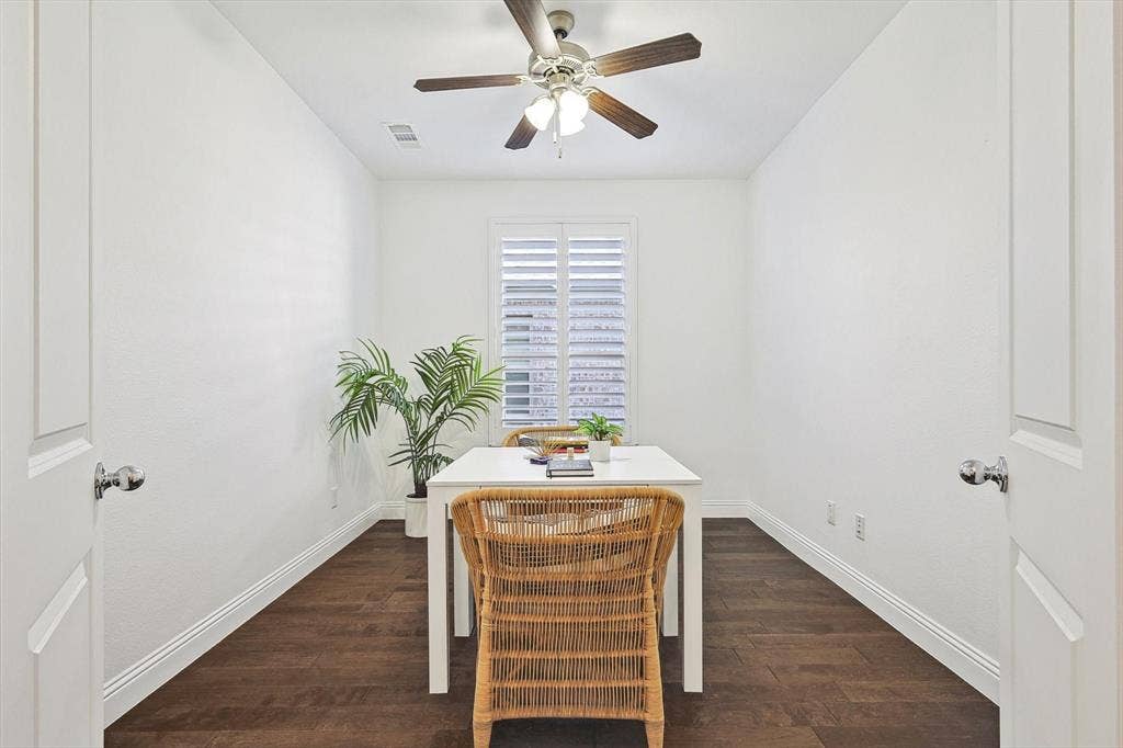 Hardwood-style flooring, window with plantation shutters, ceiling fan with integrated lighting, and white baseboards
