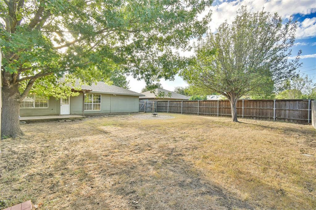 2108 8th Street, Brownwood, TX 76801 Expansive backyard featuring a wood privacy fence, mature trees, and a concrete patio