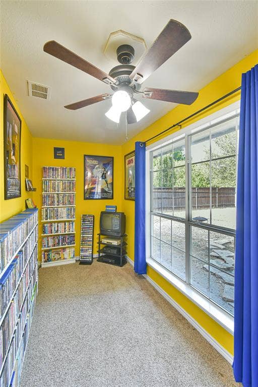 2108 8th Street, Brownwood, TX 76801 Window with grid pattern, overhead ceiling fan, and light-colored carpet flooring