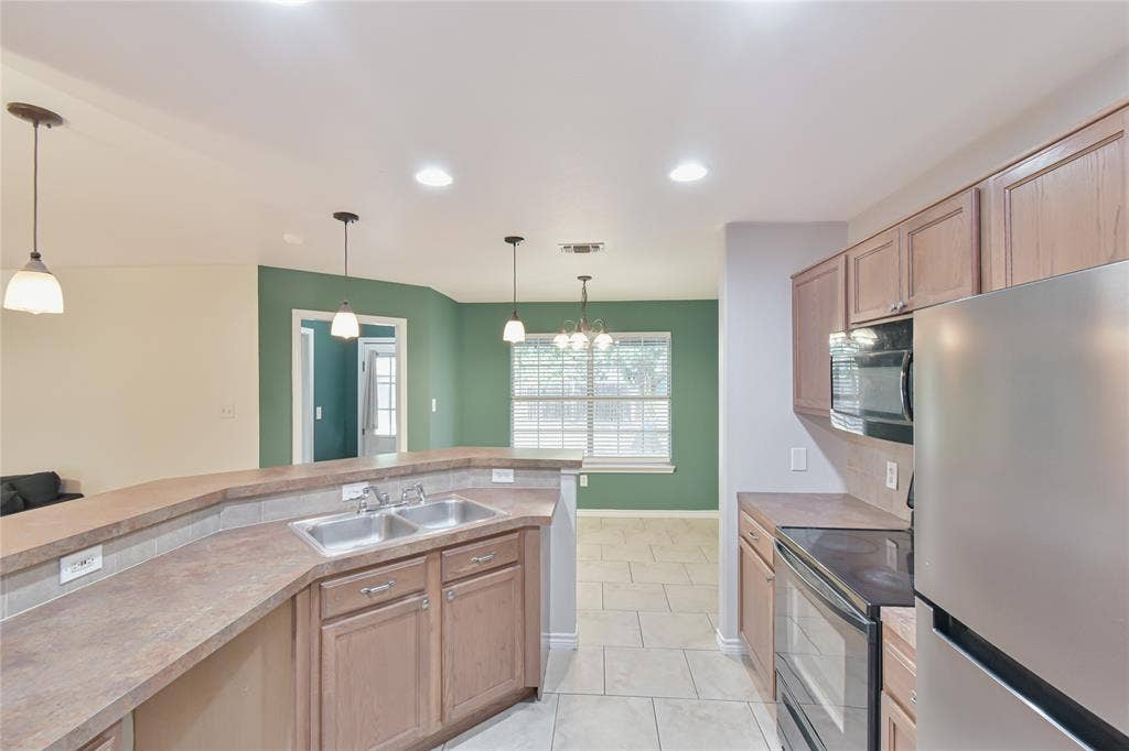 2108 8th Street, Brownwood, TX 76801 Kitchen featuring a stainless steel double sink, light wood-finish cabinetry, stainless steel refrigerator, built-in microwave, and tile flooring
