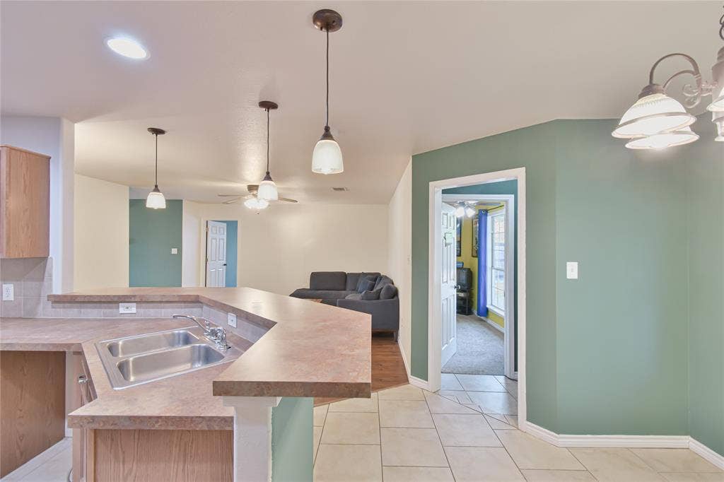 2108 8th Street, Brownwood, TX 76801 Kitchen island with a double basin stainless steel sink, laminate countertops, recessed lighting, and pendant lighting