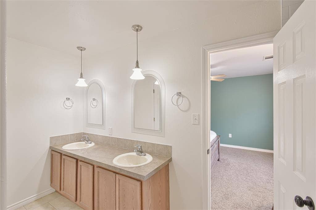2108 8th Street, Brownwood, TX 76801 Double vanity with neutral countertop and integrated sinks, accented by pendant lighting and individual arched mirrors
