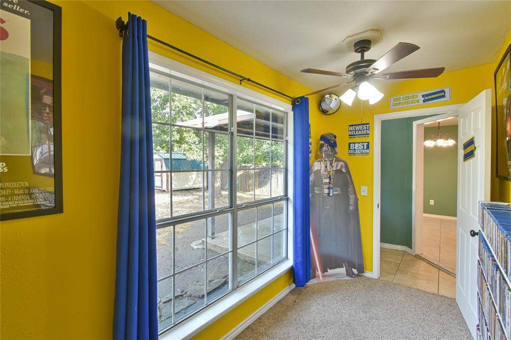 2108 8th Street, Brownwood, TX 76801 Carpeted room with a multi-pane window, ceiling fan with light fixture, and a white paneled door