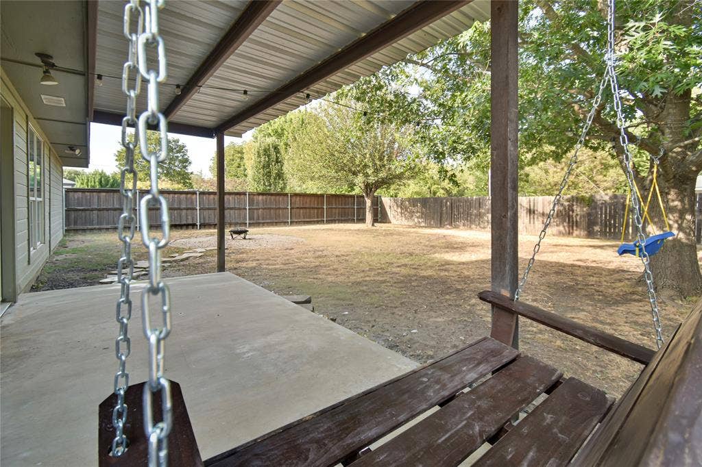 2108 8th Street, Brownwood, TX 76801 Covered concrete patio with a wood-slat porch swing and a fully fenced yard
