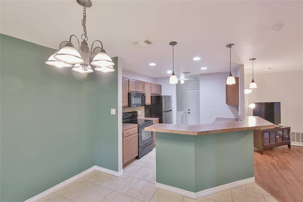 2108 8th Street, Brownwood, TX 76801 Kitchen featuring wood-finish cabinetry, black appliances, and a breakfast bar with pendant lighting