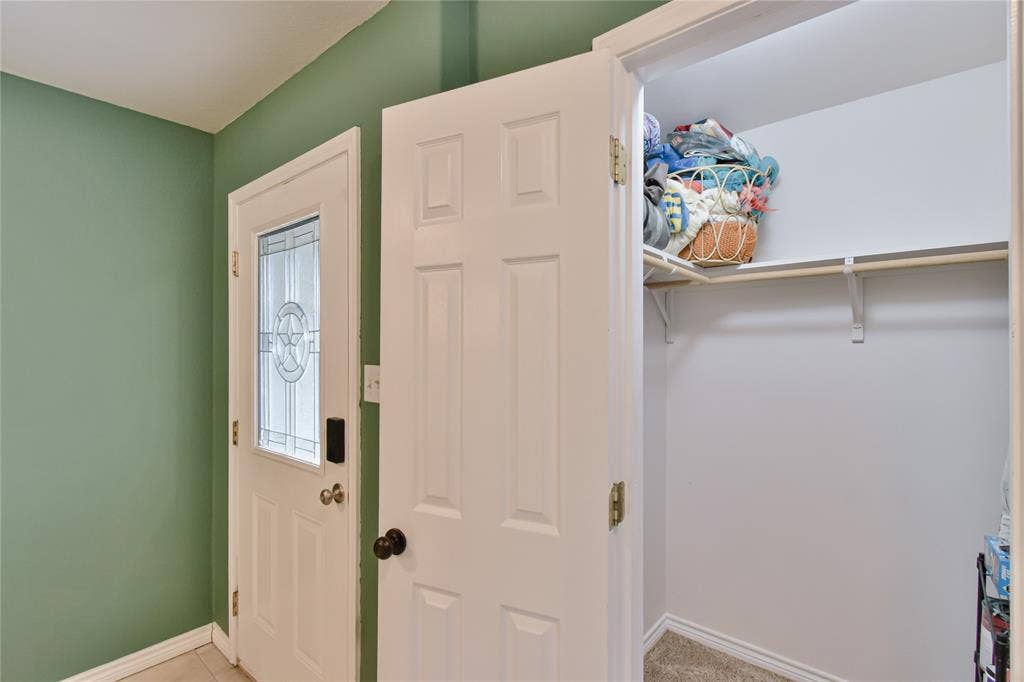 2108 8th Street, Brownwood, TX 76801 Entryway featuring a white paneled door with decorative glass, a white six-panel interior door, and a built-in closet with shelving and a hanging rod