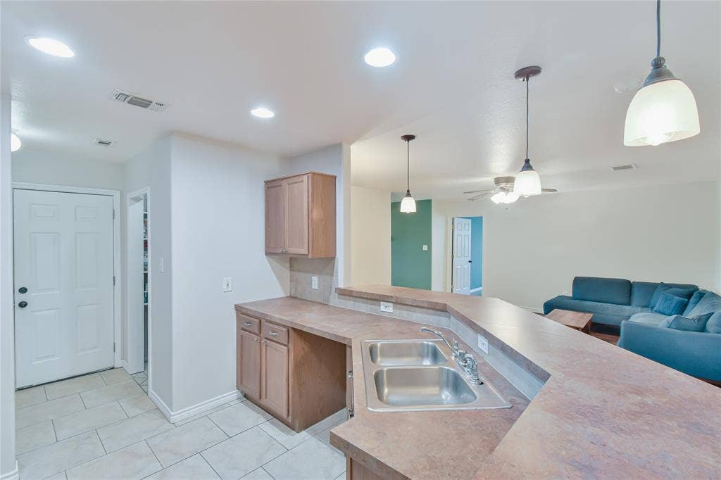 2108 8th Street, Brownwood, TX 76801 Kitchen features a stainless steel double sink, wood-finish cabinetry, and solid surface countertops