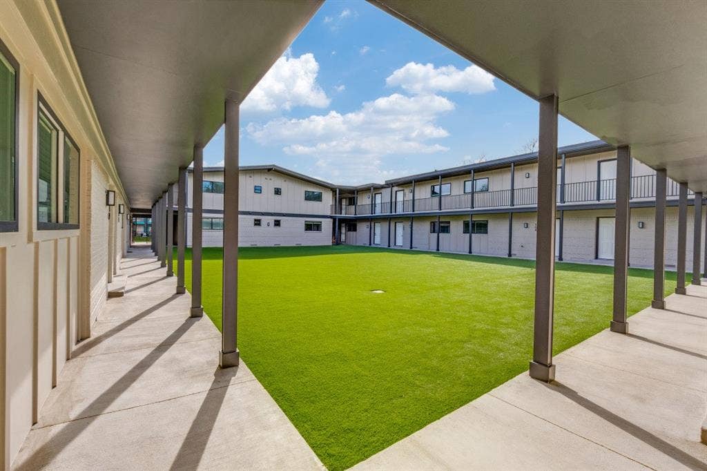 5917 Gaston Avenue, #115, Dallas, TX 75214 Central courtyard with artificial turf, surrounded by two-story buildings featuring balconies, covered walkways, and modern exterior lighting