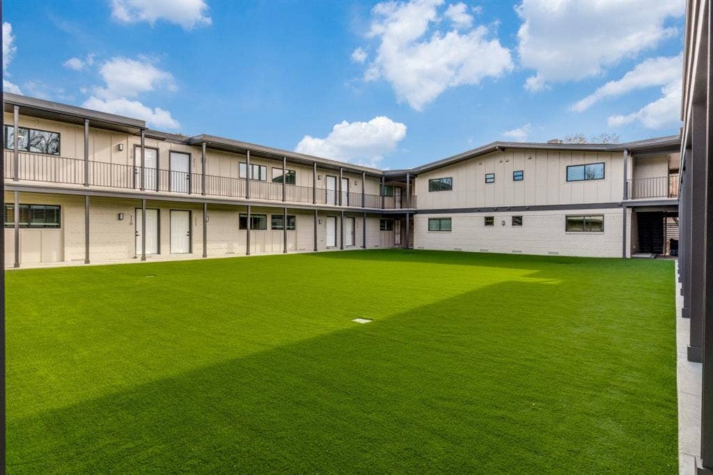 5917 Gaston Avenue, #115, Dallas, TX 75214 Expansive artificial turf courtyard surrounded by a multi-story building featuring exterior walkways and balconies with dark metal railings