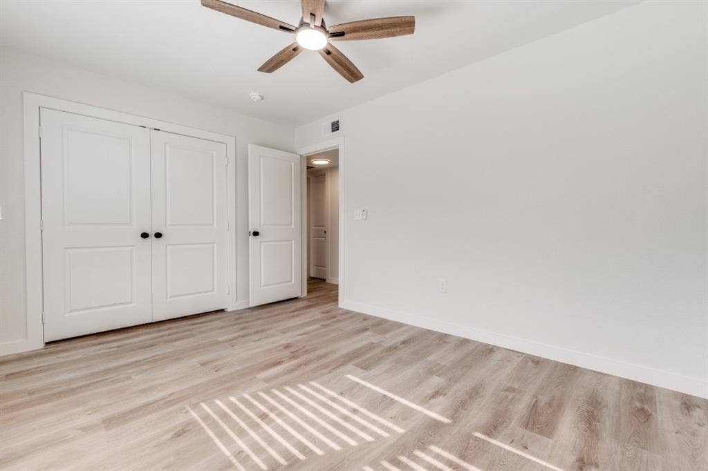 5917 Gaston Avenue, #115, Dallas, TX 75214 Wood-finish flooring, white walls, ceiling fan with integrated lighting, and white bi-fold closet doors