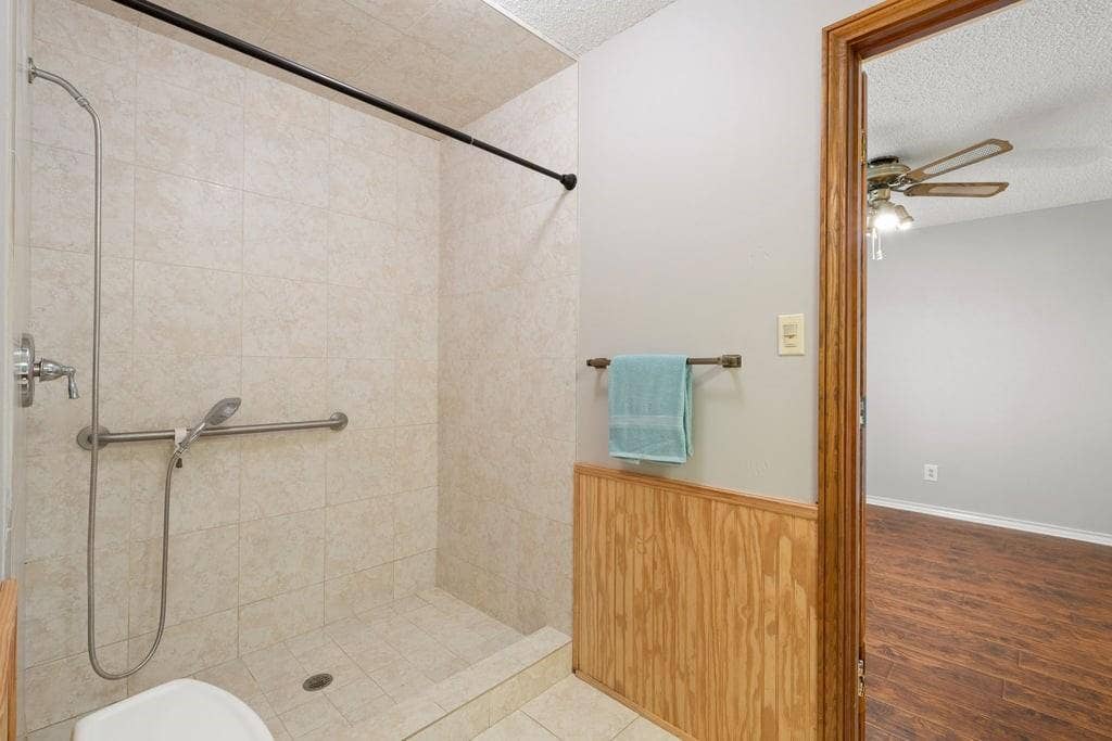 Tiled shower with grab bar and handheld shower fixture