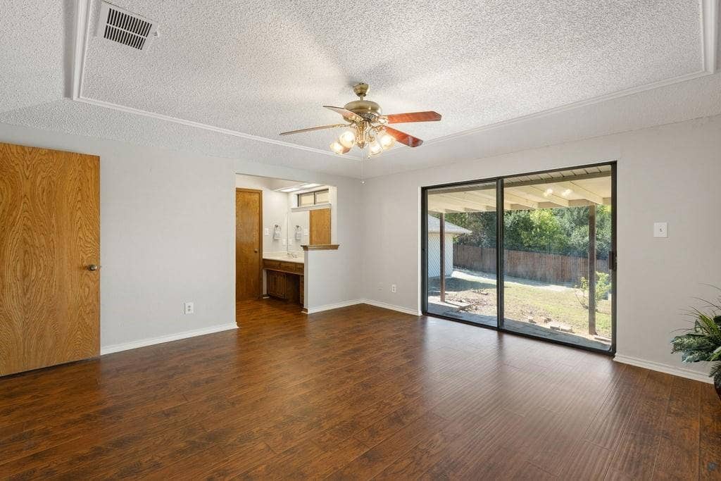 Wood-finish flooring, tray ceiling with ceiling fan, and sliding glass doors