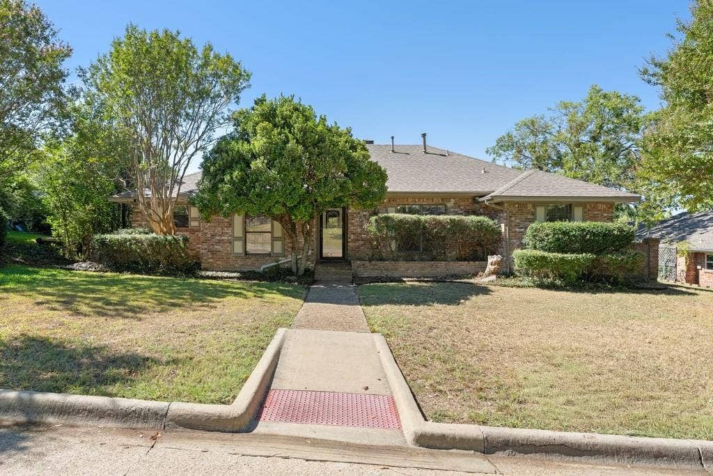 Brick exterior with a gabled roof and mature landscaping