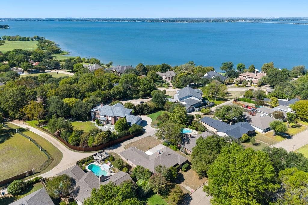 Waterfront property with extensive landscaping, mature trees, and an in-ground swimming pool