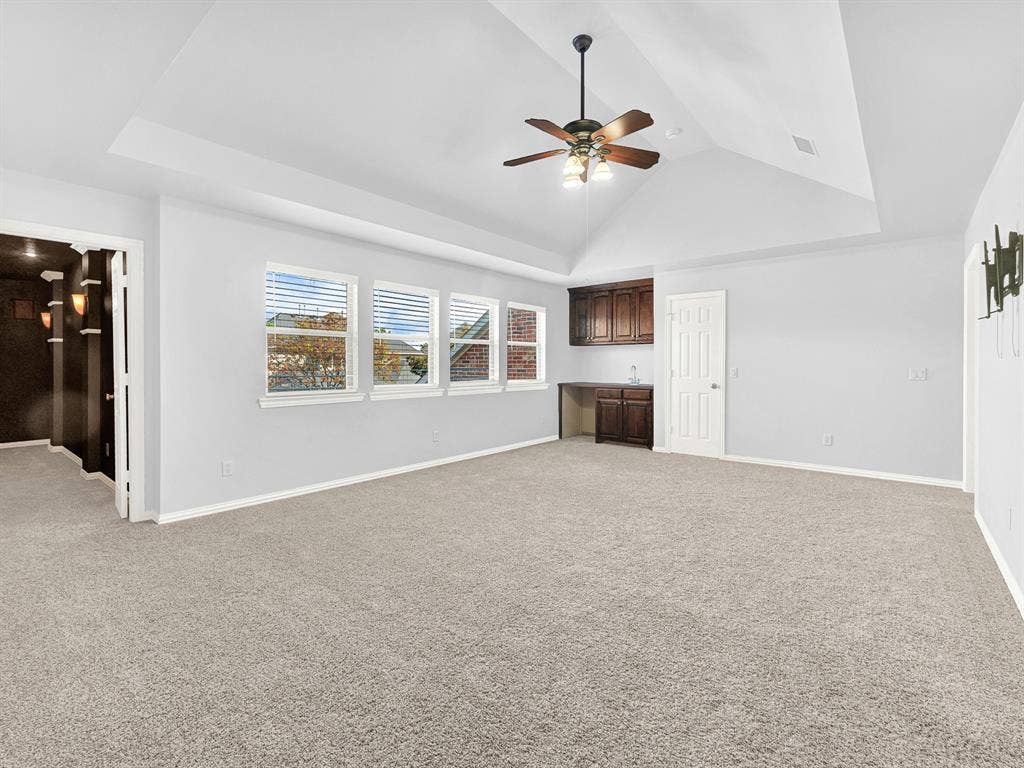 10222 Plainsman Lane, Frisco, TX 75035 Tray ceiling with ceiling fan, built-in cabinetry with a sink, light gray walls, and carpet flooring
