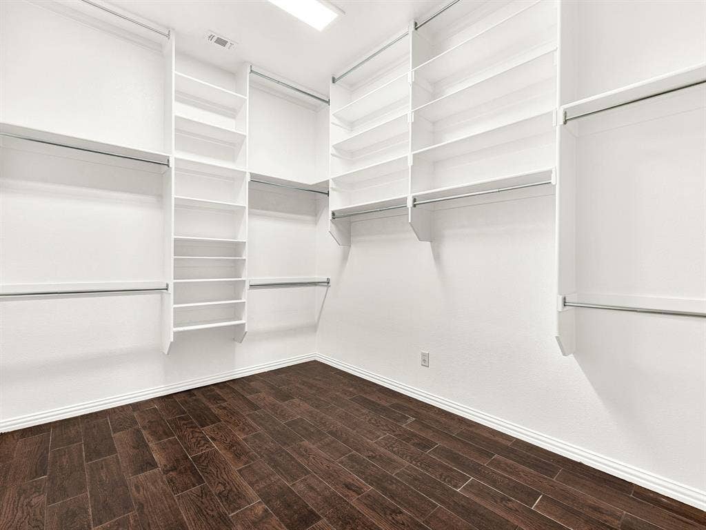 10222 Plainsman Lane, Frisco, TX 75035 Custom closet system with built-in shelving, multiple hanging rods, and dark wood-finish flooring