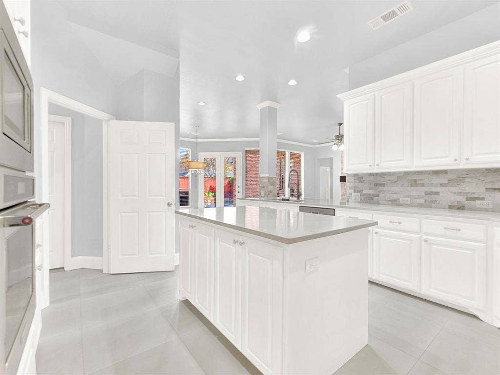 10222 Plainsman Lane, Frisco, TX 75035 Kitchen featuring white cabinetry, light gray countertops, a tile backsplash, stainless steel appliances, and large format floor tiling
