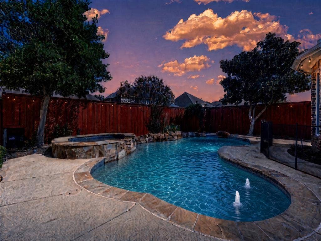 10222 Plainsman Lane, Frisco, TX 75035 Freeform swimming pool with stone coping, an integrated spa with stone surround, and decorative water features