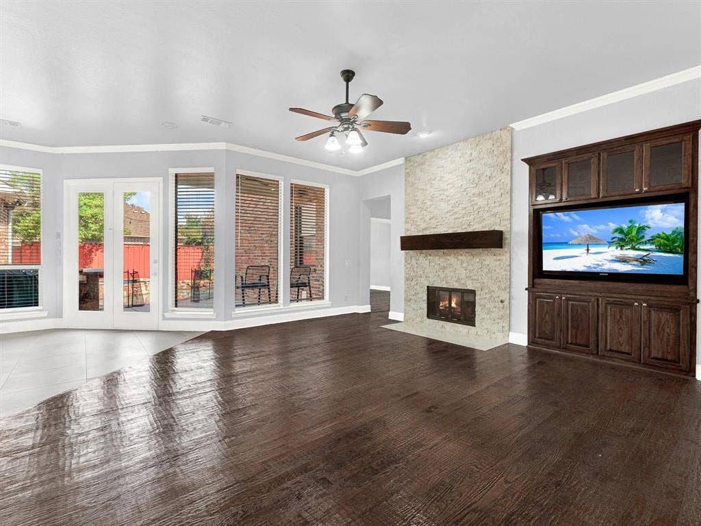 10222 Plainsman Lane, Frisco, TX 75035 Expansive living area with wood-finish flooring, a stone-clad fireplace, and a built-in entertainment center