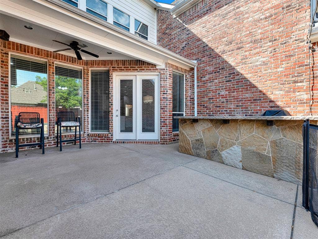 10222 Plainsman Lane, Frisco, TX 75035 Covered patio with a ceiling fan, concrete flooring, and a built-in stone-clad outdoor kitchen