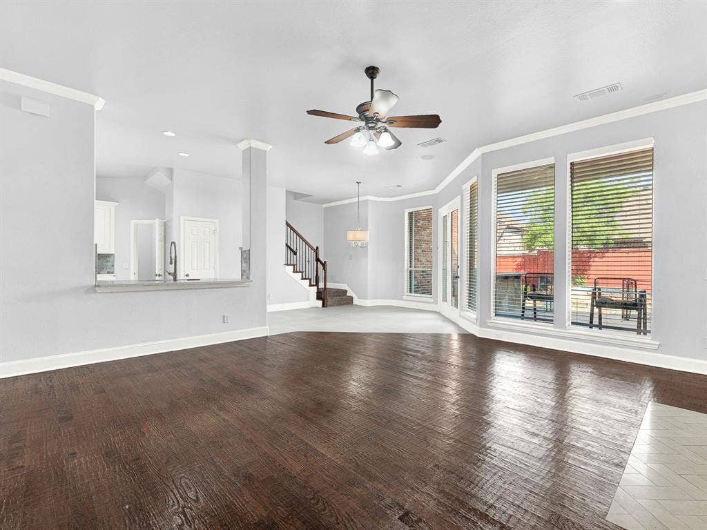 10222 Plainsman Lane, Frisco, TX 75035 Wood-finish flooring, bay window with multiple panes, ceiling fan light fixture, staircase with wood handrail, and a built-in half-wall with countertop