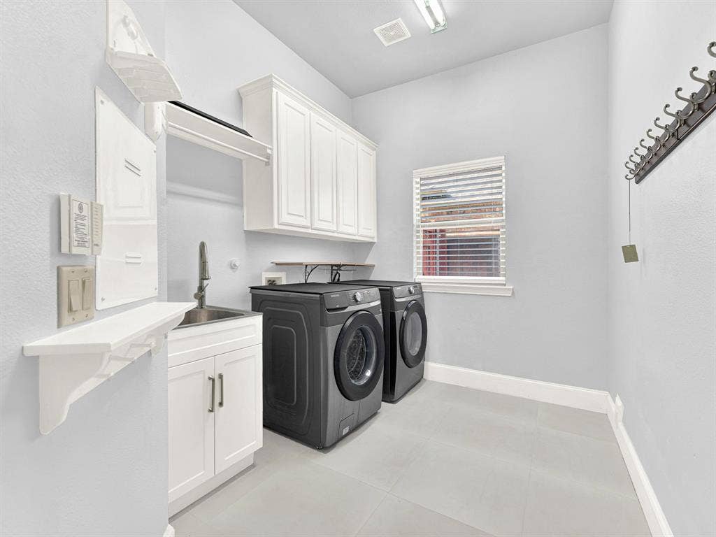 10222 Plainsman Lane, Frisco, TX 75035 White shaker-style cabinetry, stainless steel sink, light-colored tile flooring, and a window with blinds