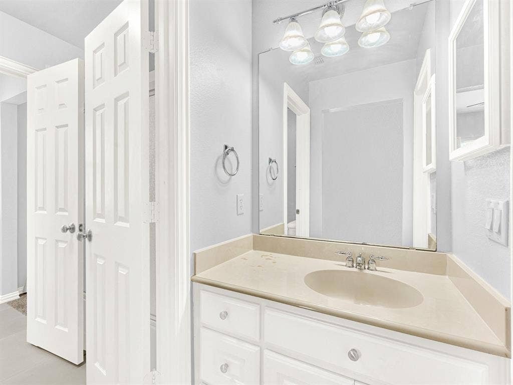 10222 Plainsman Lane, Frisco, TX 75035 Built-in vanity with an integrated sink, polished chrome faucet, and expansive wall mirror