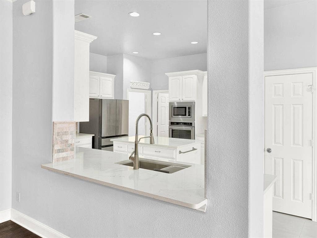 10222 Plainsman Lane, Frisco, TX 75035 Kitchen pass-through featuring a white countertop with an undermount sink and a gooseneck faucet