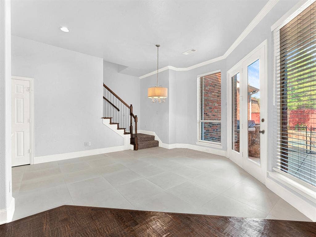 10222 Plainsman Lane, Frisco, TX 75035 Light gray tiled flooring, built-in staircase with wood railing, double French doors, large windows, and a chandelier lighting fixture