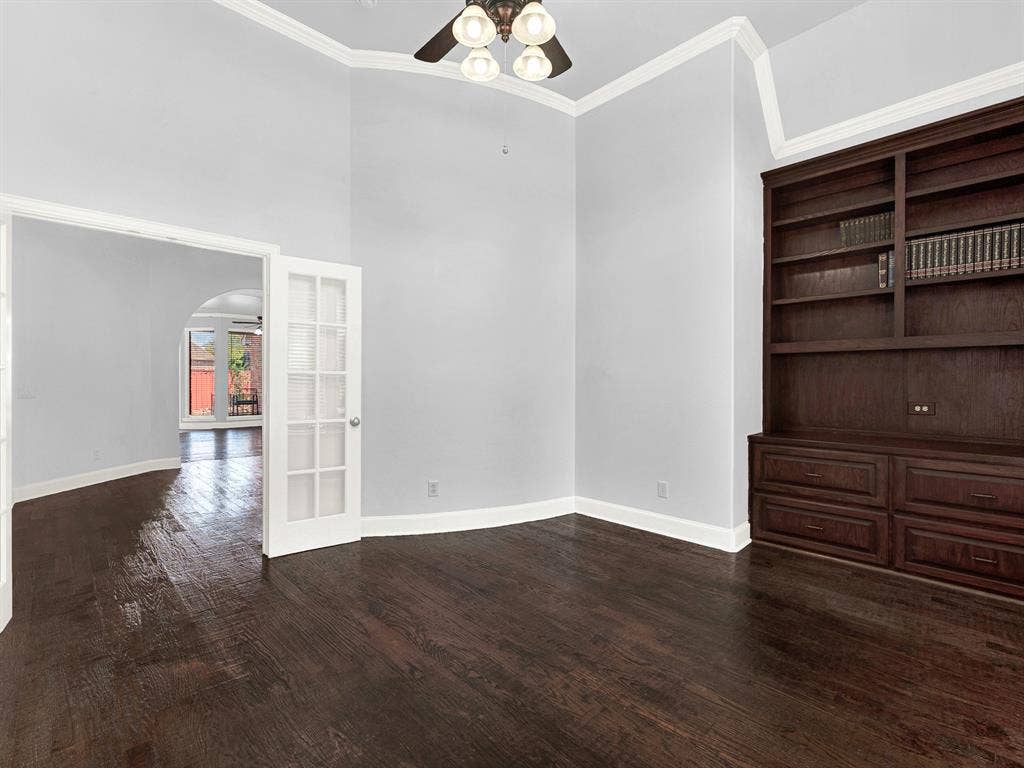 10222 Plainsman Lane, Frisco, TX 75035 Dark wood-finish flooring, built-in shelving with lower cabinetry, and crown molding