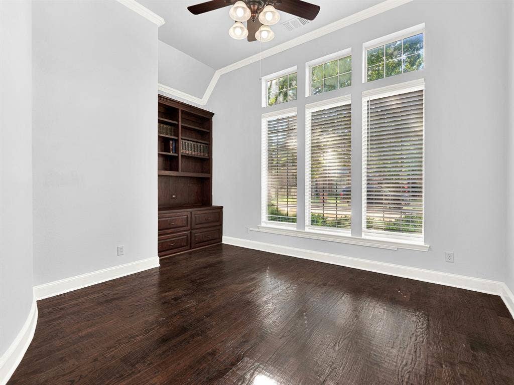 10222 Plainsman Lane, Frisco, TX 75035 Built-in dark wood cabinetry with shelving, dark wood-finish flooring, and multiple tall windows with blinds