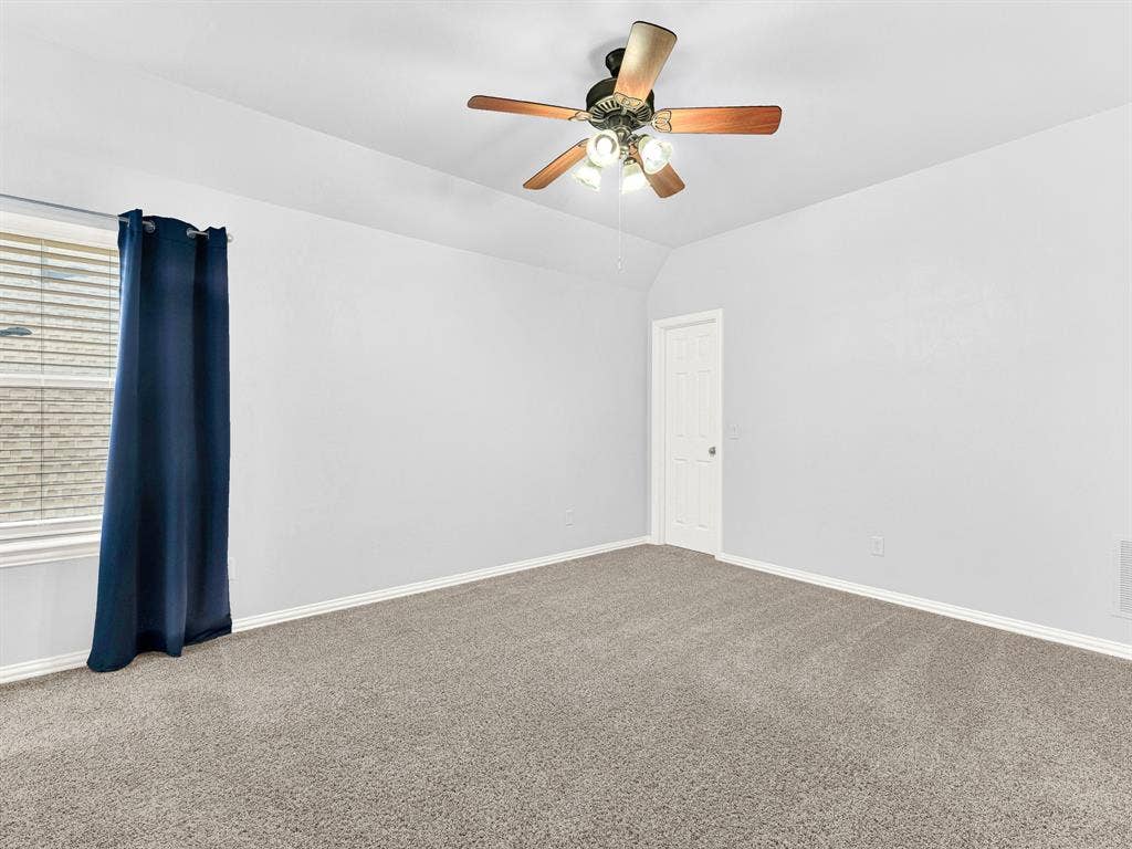 10222 Plainsman Lane, Frisco, TX 75035 Vaulted ceiling with a ceiling fan light fixture, light gray walls, gray carpet flooring, and a white window with blinds