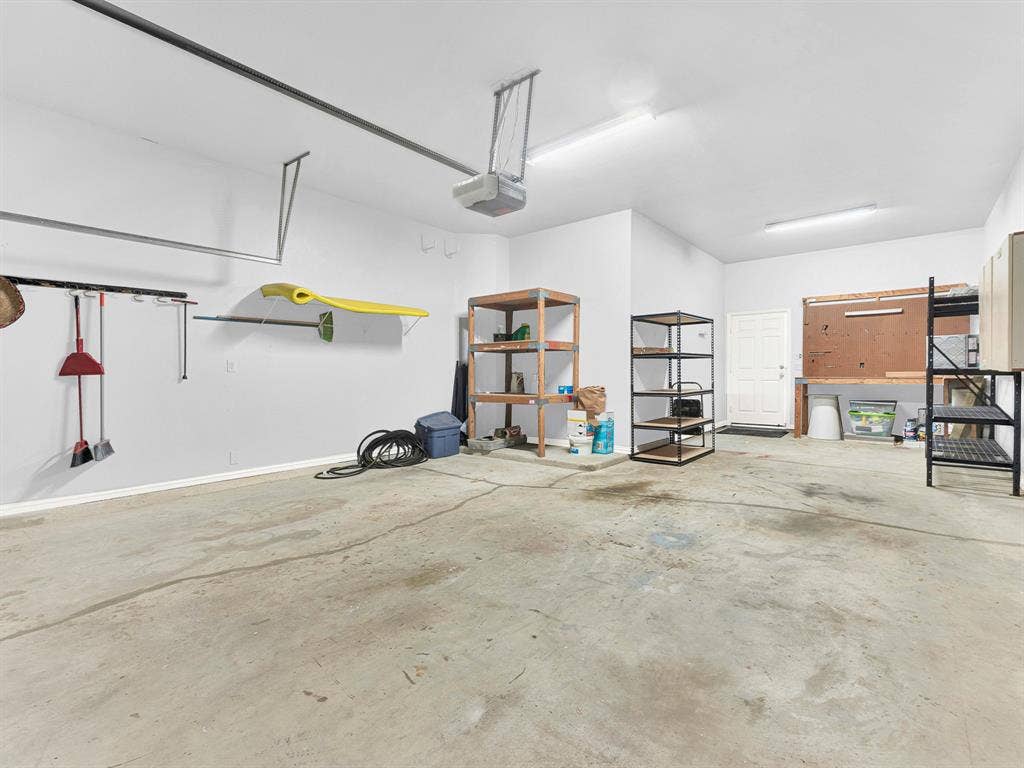 10222 Plainsman Lane, Frisco, TX 75035 Spacious garage with exposed concrete flooring, white walls, and overhead fluorescent lighting