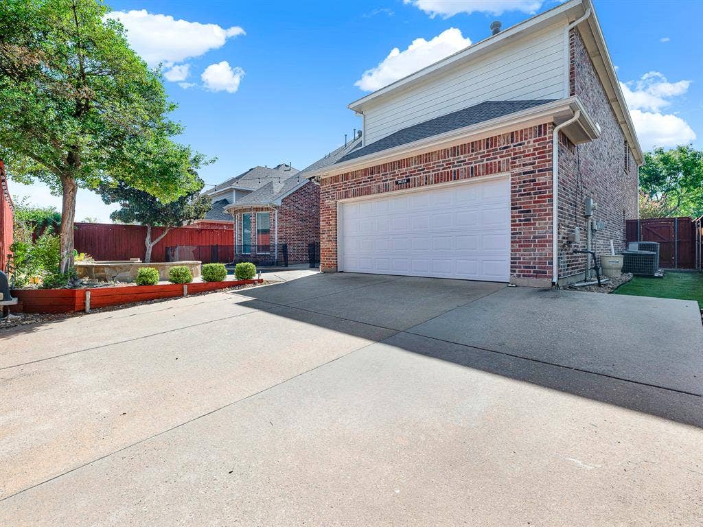 10222 Plainsman Lane, Frisco, TX 75035 Brick facade with white siding, attached garage, concrete driveway, and a fenced yard