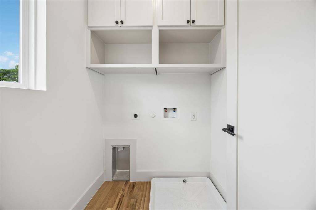 White shaker cabinetry with black hardware, wood-finish flooring, and a white window frame