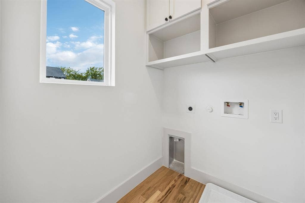 Dedicated laundry room featuring built-in white cabinetry with open shelving